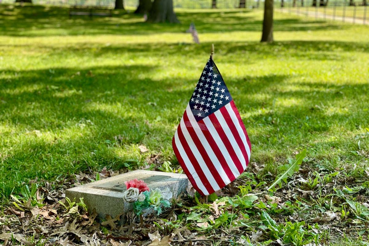 An American flag standing beside a Veteran headstone